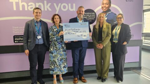 Group of people posing for photo holding big charity cheque