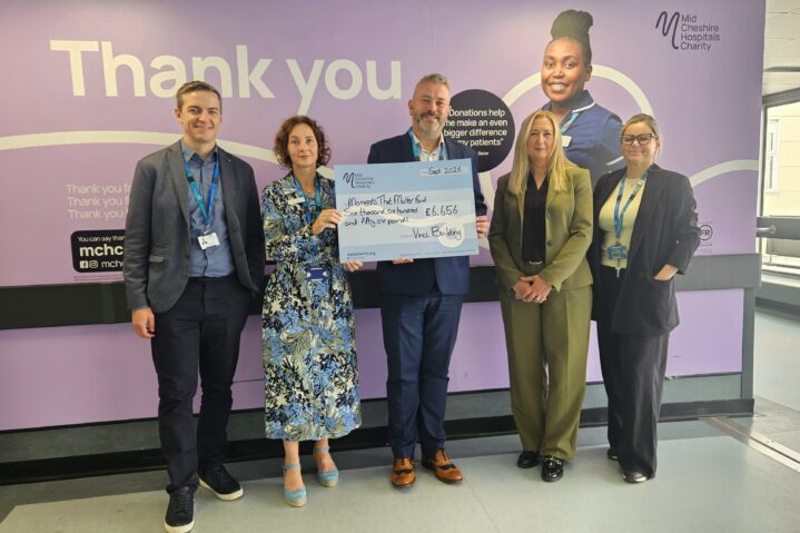 Group of people posing for photo holding big charity cheque